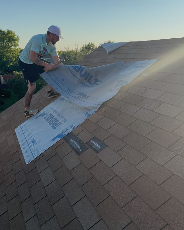 Roofer laying synthetic underlayment during a roof repair in Forney, TX